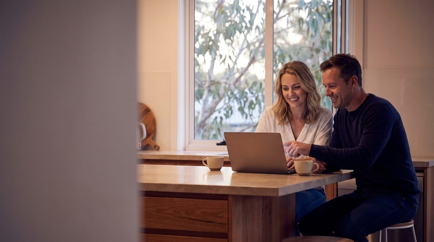 A couple at their kitchen bench discovering what refinancing could save